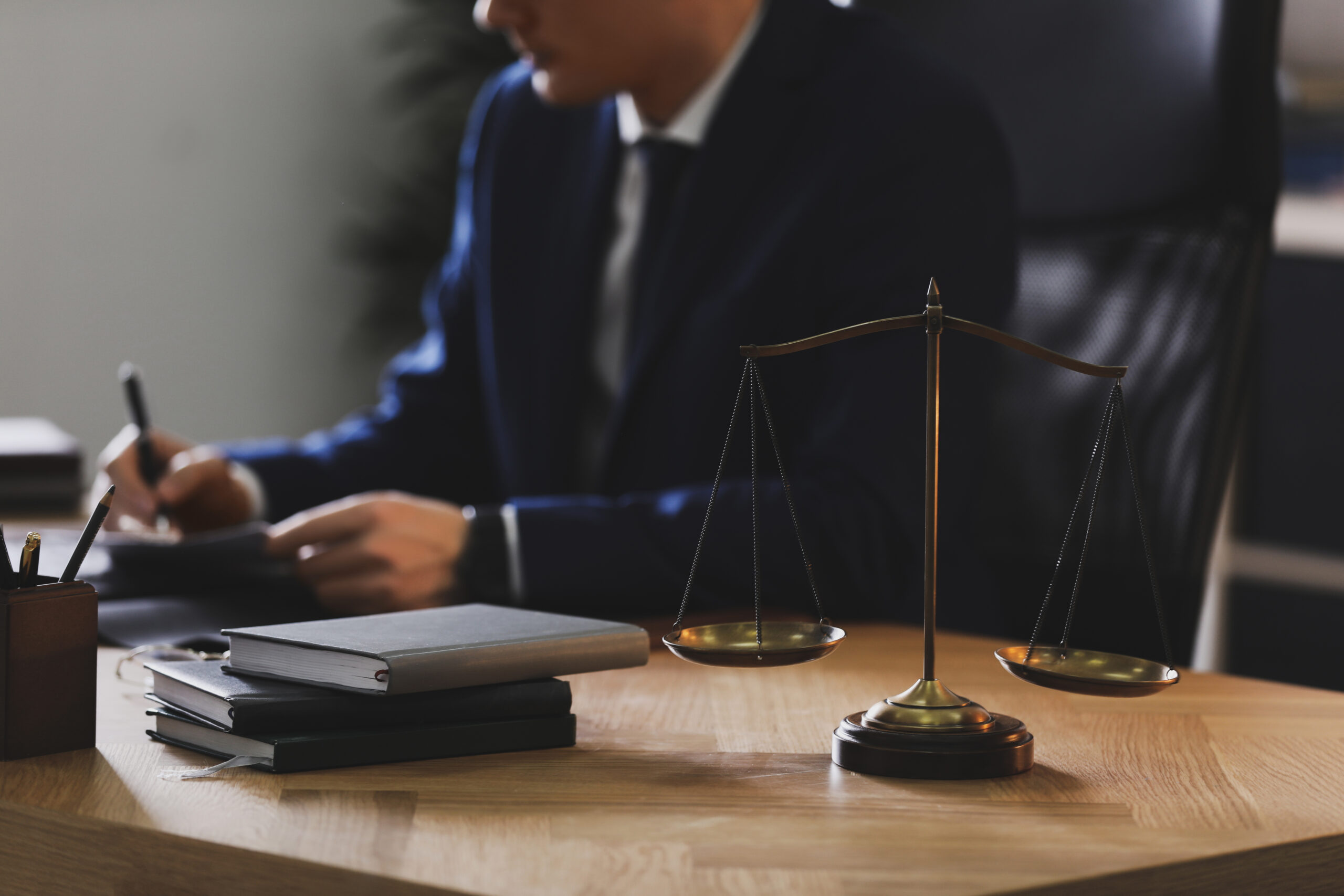 Attorney working at a table with books and a scale in the foreground.